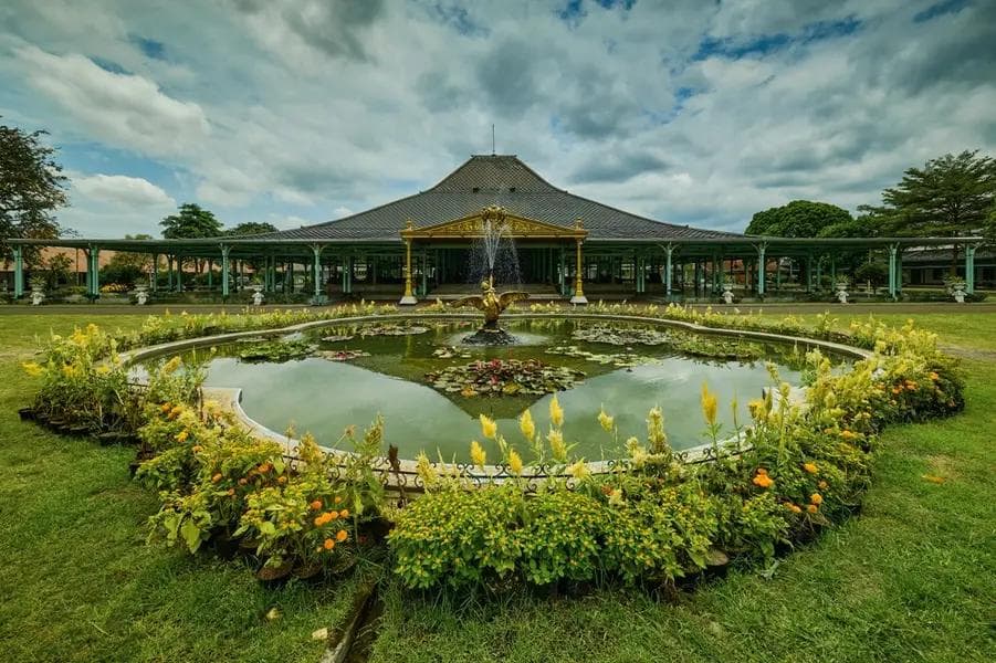 Puro Mangkunegaran in Solo, Central Java, with green grounds beneath a bright sky.