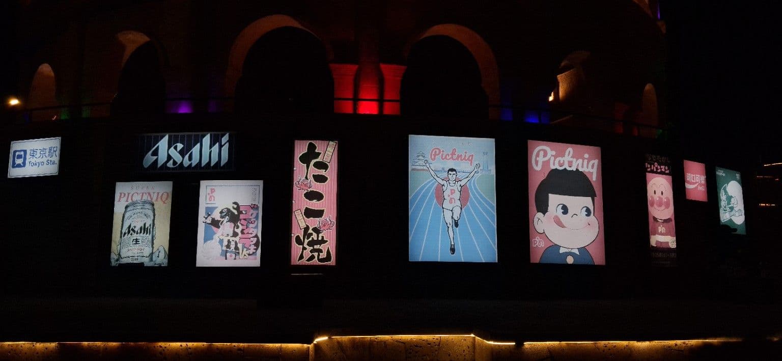 Illuminated Japan-themed poster wall at PICTNIQ Jogja at night
